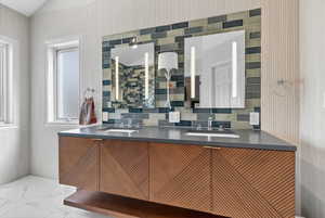 Dual vanity featuring a wood-finish cabinet with textured geometric panels, integrated sinks, and matte gray countertops
