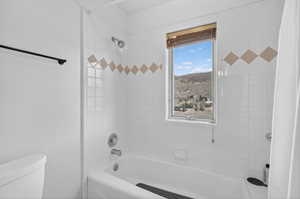 Bathroom featuring a white subway tile surround with decorative diamond accents, a fixed window with wood-tone blinds, a bathtub with chrome fixtures, and a wall-mounted shower head
