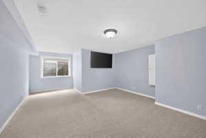 Spacious room featuring light blue walls, beige carpet, and white trim