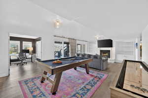 Spacious recreation room featuring wood-finish flooring, a built-in fireplace with tile surround, and expansive built-in shelving