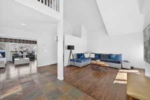 Vaulted ceilings highlight this living space, featuring wood-finish flooring and a partial wall separating spaces
