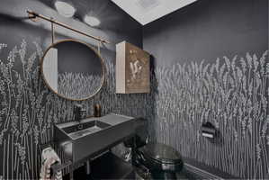 Powder room featuring dark-toned walls with a botanical stencil pattern