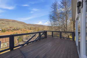 Spacious outdoor deck featuring wood-finish flooring and dark-stained wood railings with wire mesh infill