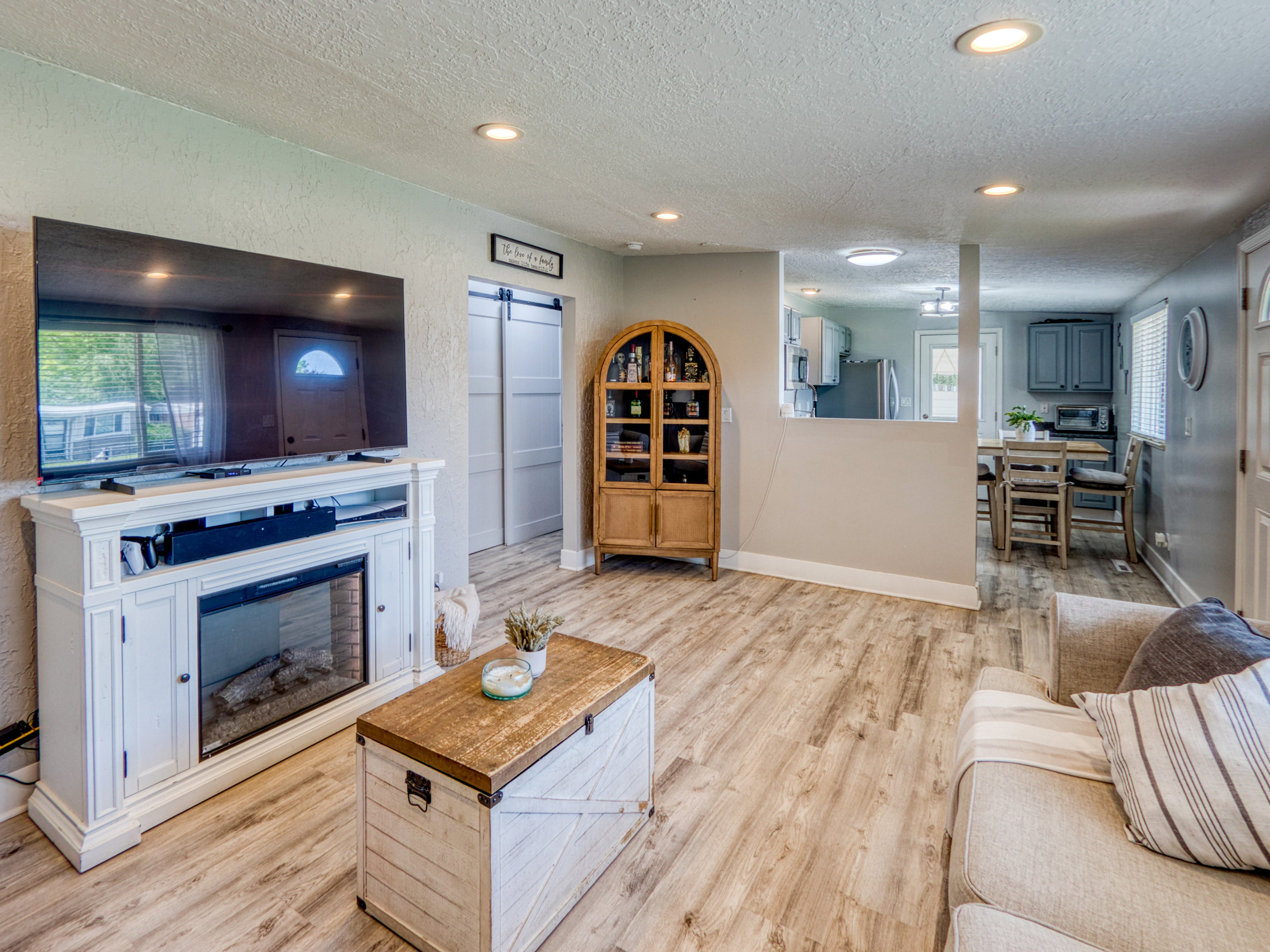 Spacious living area featuring wood-finish flooring, recessed lighting, and a partial wall opening to the kitchen