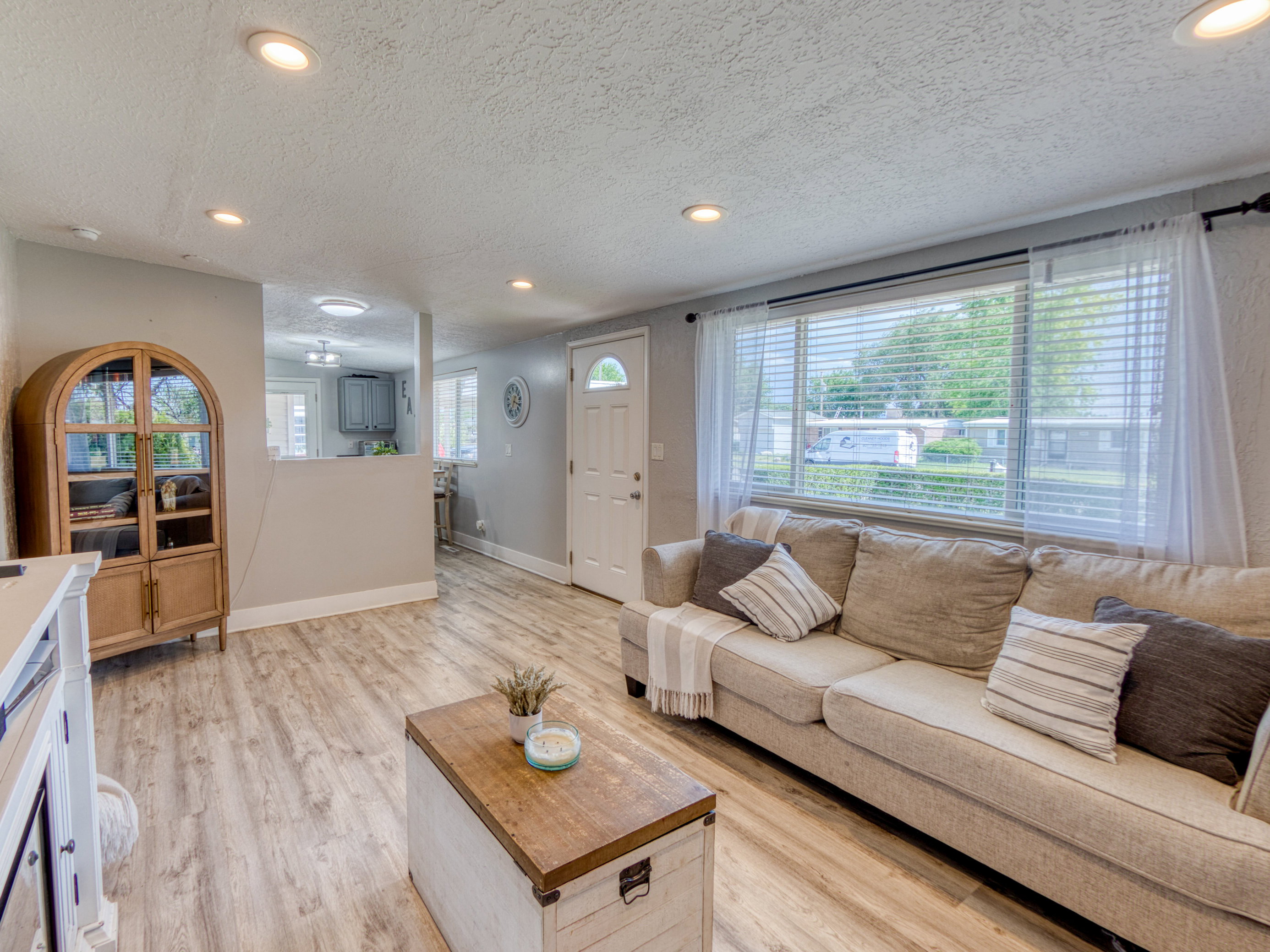 Spacious living area featuring wood-finish flooring, recessed lighting, and a large window with horizontal blinds