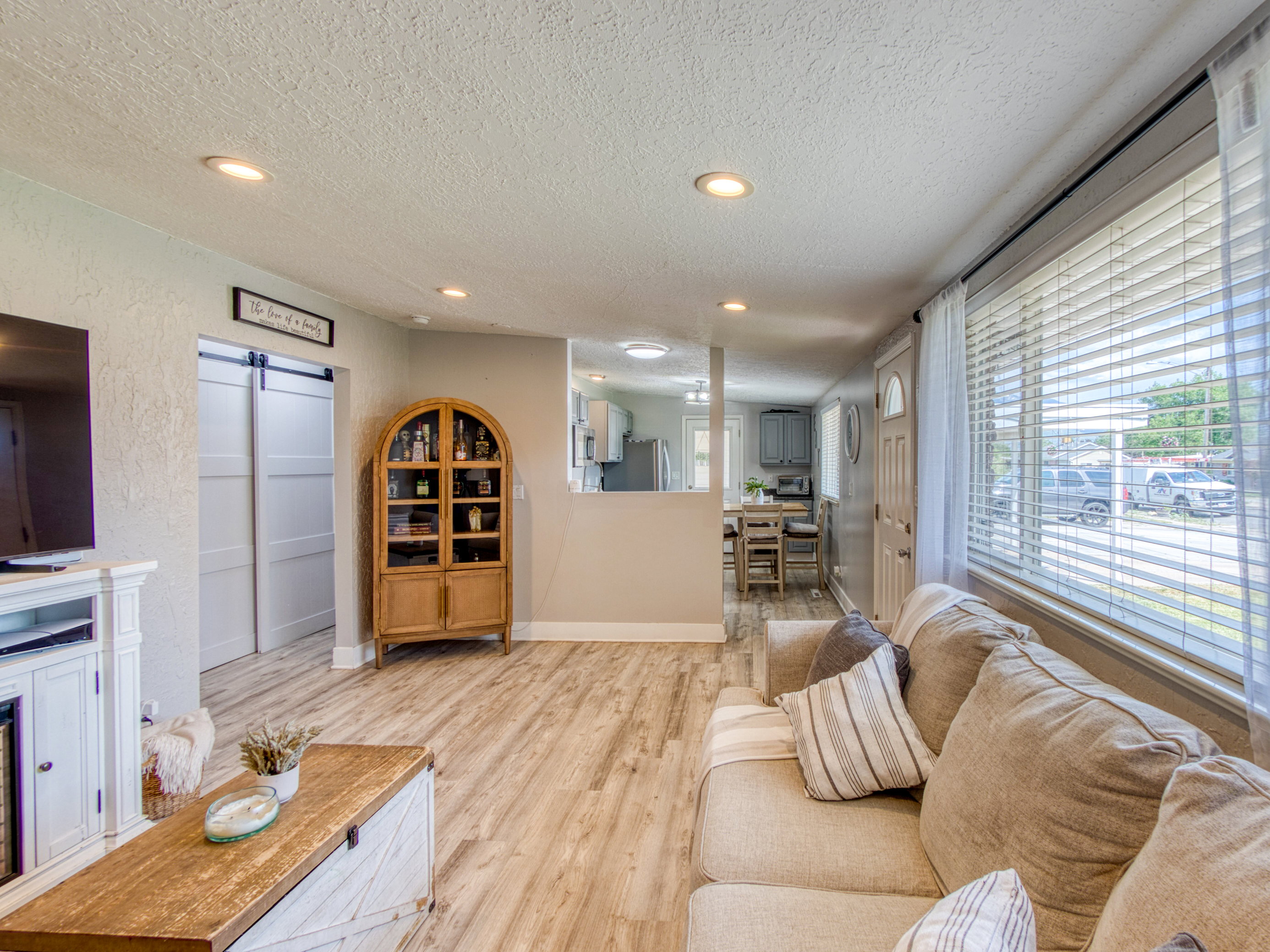Spacious living area featuring wood-finish flooring, recessed lighting, and large windows with blinds