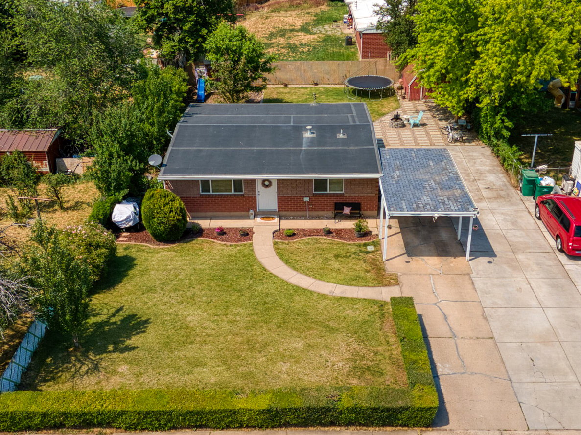Red brick residence featuring a charcoal shingle roof, a curving concrete pathway, and a covered carport with a flat roof