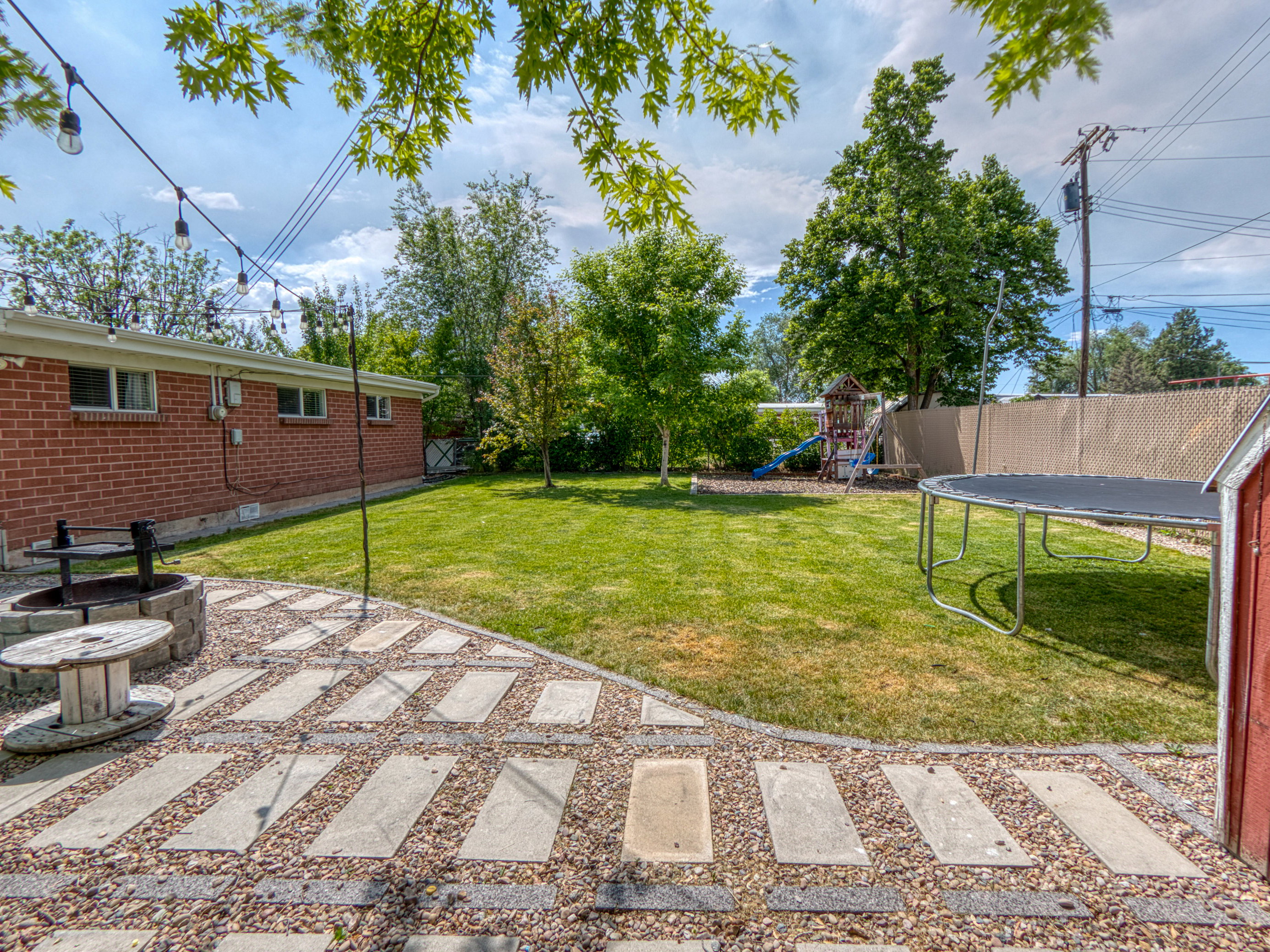 Spacious backyard featuring a stone fire pit, paver and gravel patio, and a manicured lawn