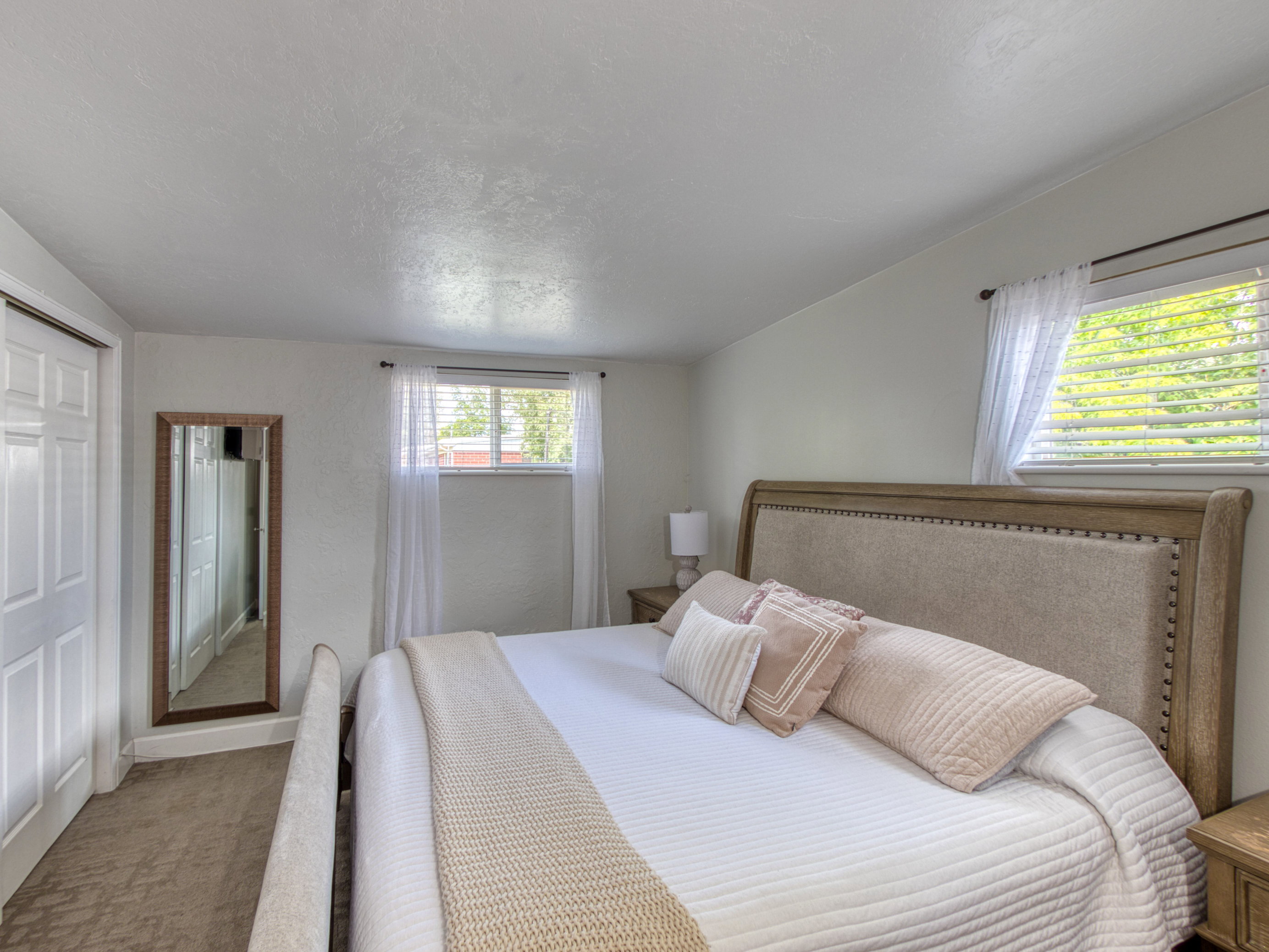 Spacious room featuring a window with blinds, a panel door, and plush carpet flooring