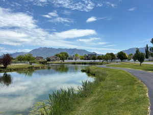 Pond-side paved pathway bordered by green lawn and natural reeds