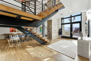Open-tread staircase with wood-finish steps and black metal railings, stone accent wall, and expansive floor-to-ceiling windows