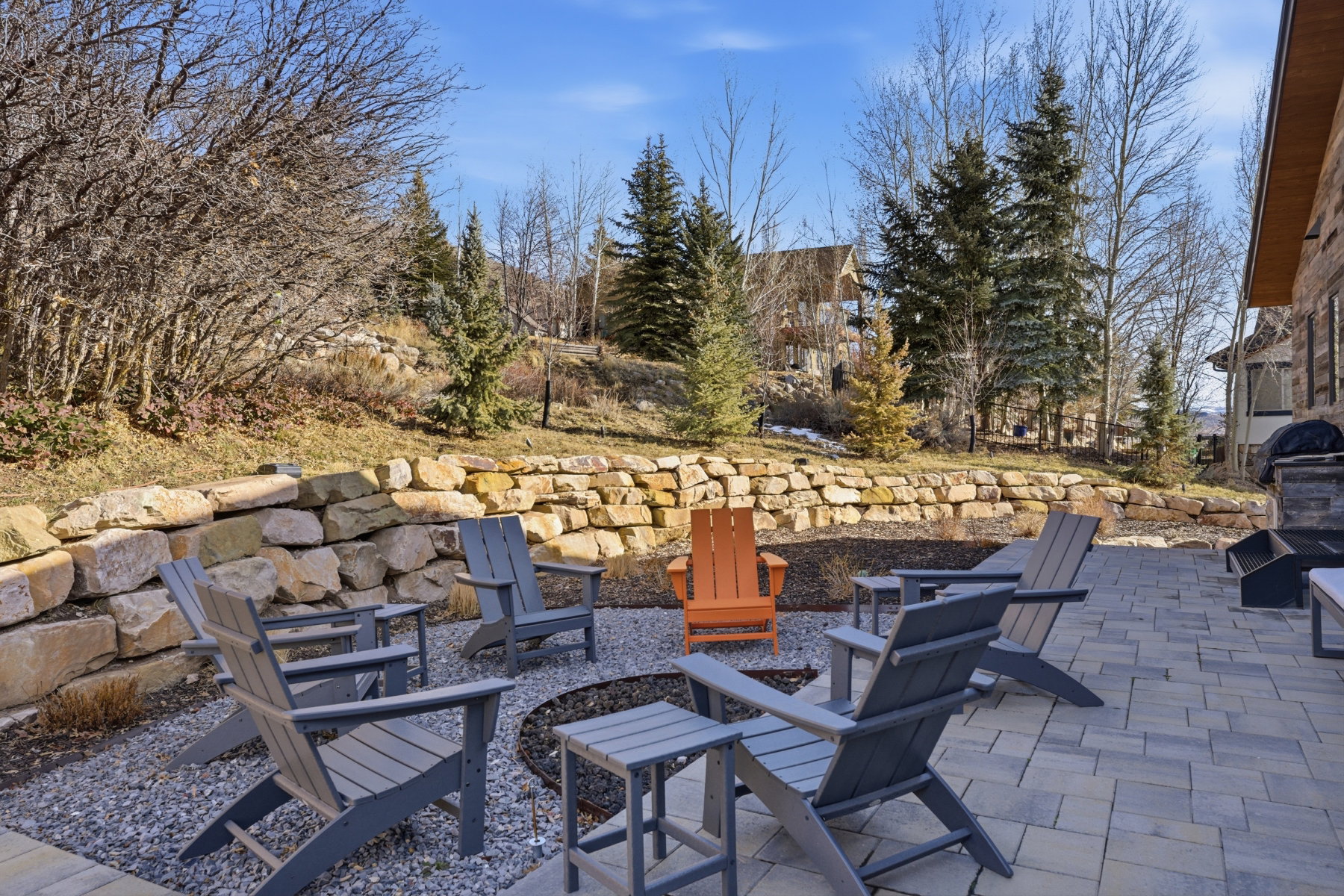 Expansive outdoor patio featuring paver stone surfacing, a stone retaining wall, and an integrated outdoor grilling station