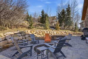 Expansive outdoor patio featuring paver stone surfacing, a stone retaining wall, and an integrated outdoor grilling station