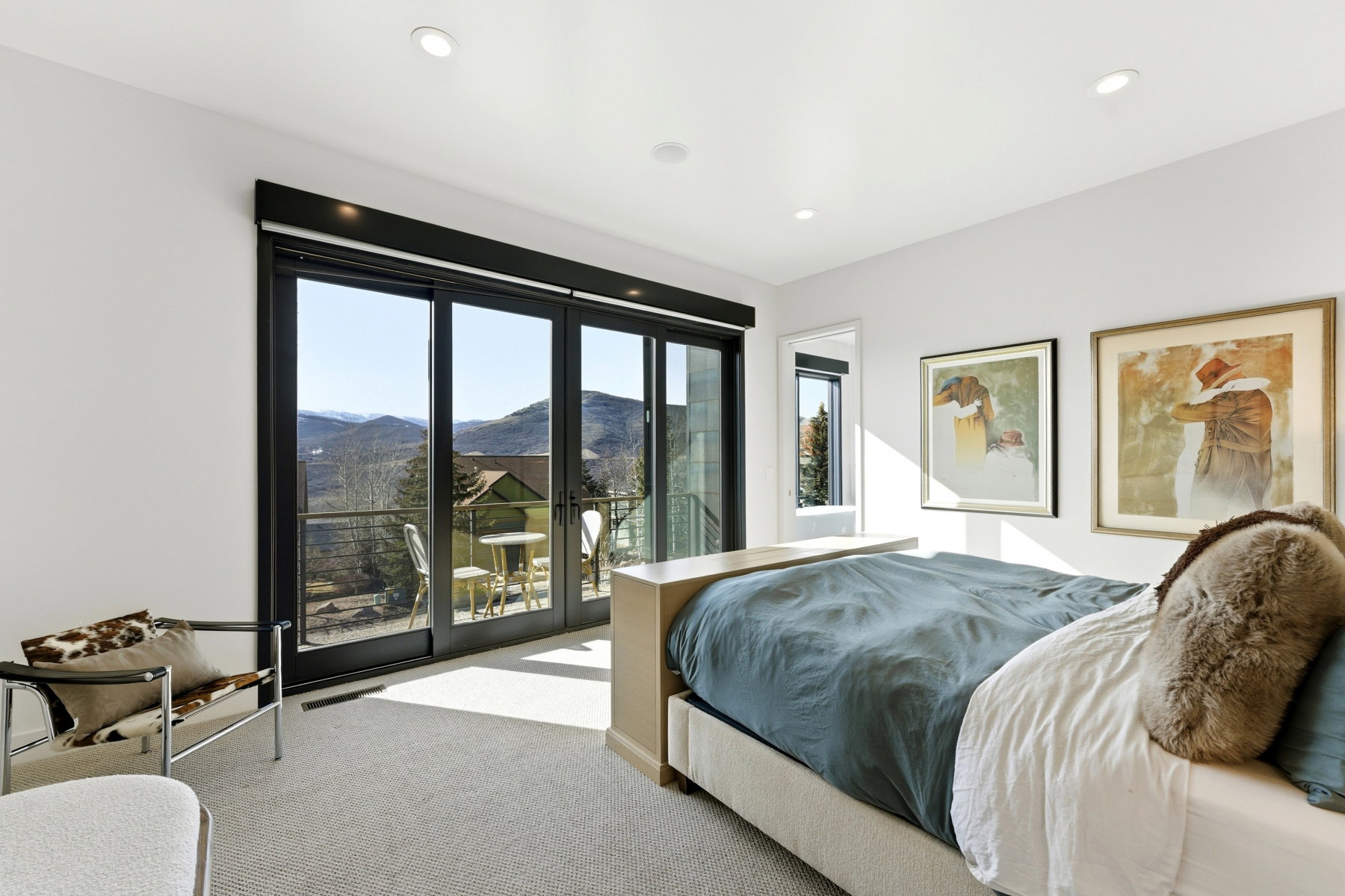 Bedroom with expansive sliding glass doors opening to a balcony, offering mountain scenery