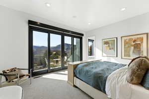Bedroom with expansive sliding glass doors opening to a balcony, offering mountain scenery