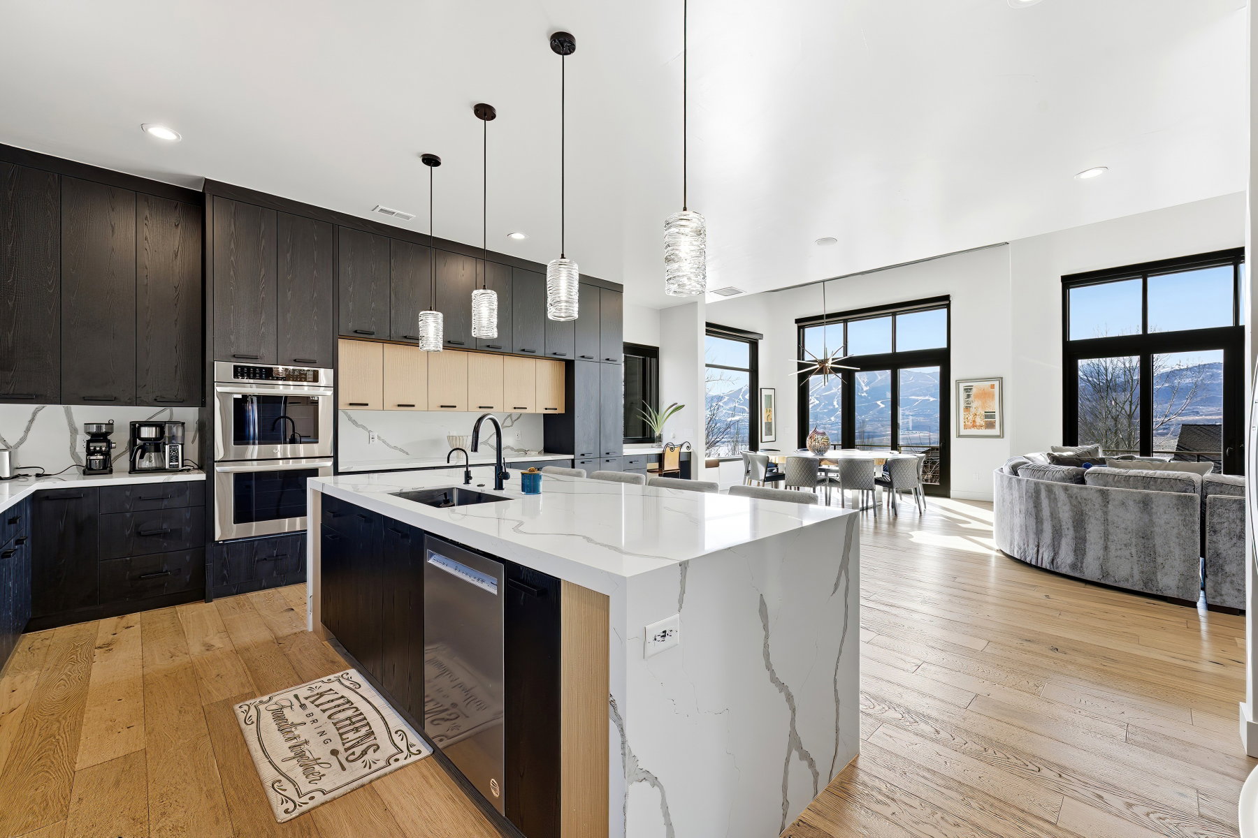 Contemporary kitchen featuring an expansive island with a waterfall countertop, integrated sink, and dishwasher