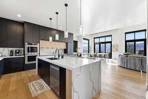 Contemporary kitchen featuring an expansive island with a waterfall countertop, integrated sink, and dishwasher