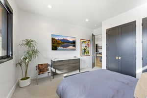 Bedroom featuring light-toned carpeting, recessed lighting, and a dark-framed window