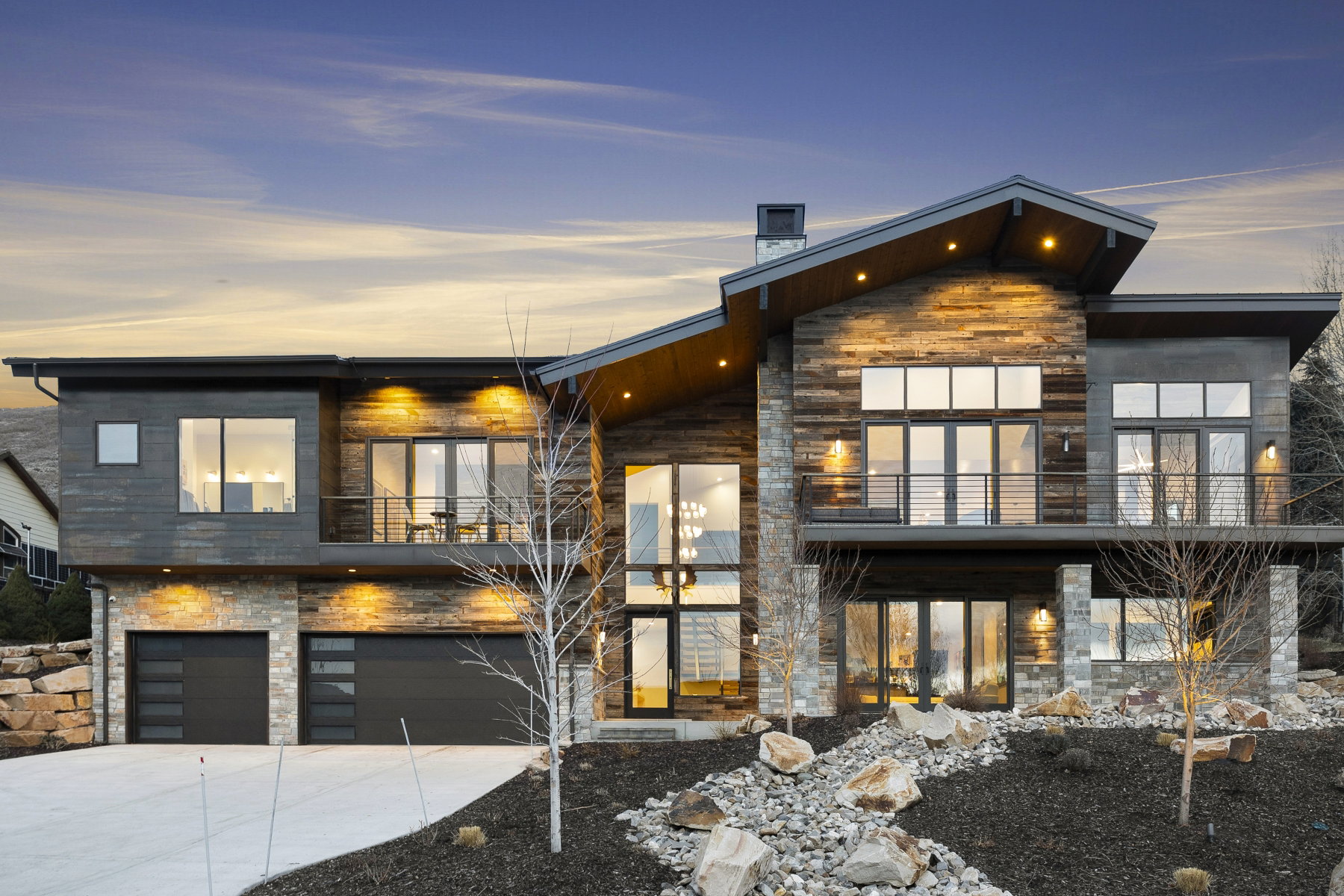 Contemporary residence featuring a multi-material facade of stone and wood-finish siding