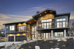 Modern architectural residence featuring multi-level design and a combination of wood-finish siding, stone accents, and dark paneling
