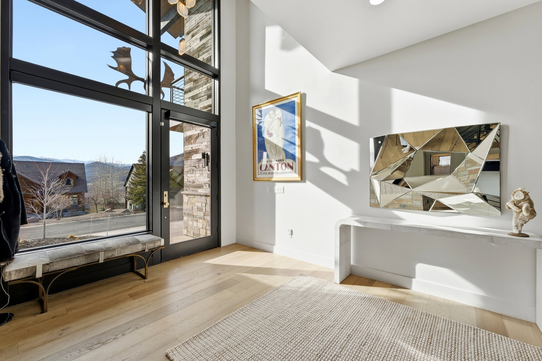 Grand entry featuring a tall door with multiple large glass panels, light wood-finish flooring, and a stone accent wall