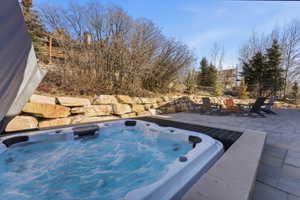 Outdoor spa with bubbling water, set into a paver patio with stone retaining walls