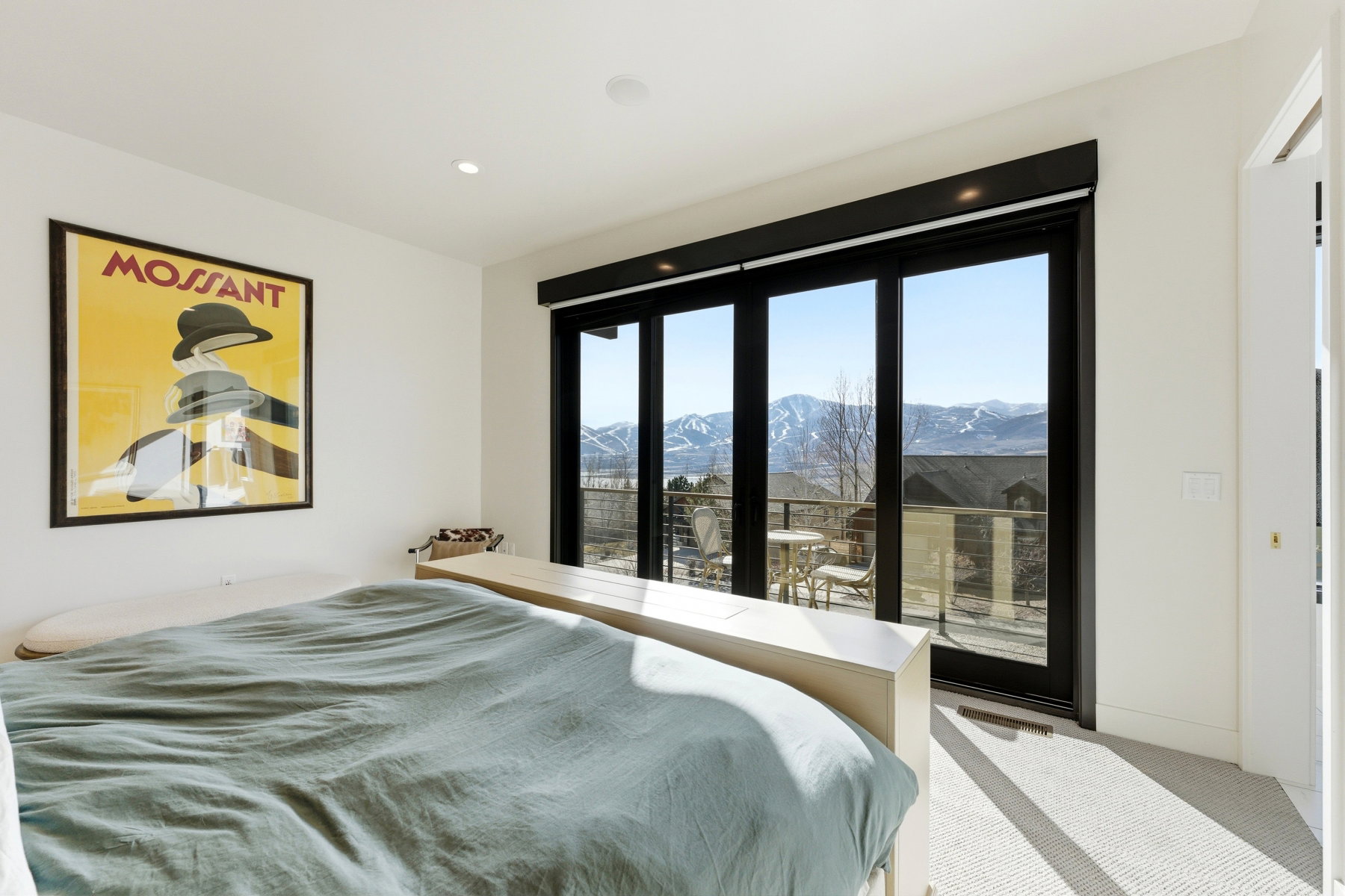 Floor-to-ceiling sliding glass doors open to a balcony with mountain scenery