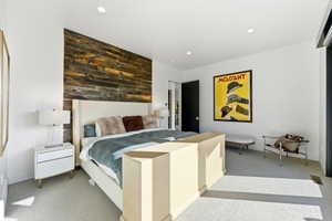Bedroom featuring a textured wood accent wall and light gray carpeting