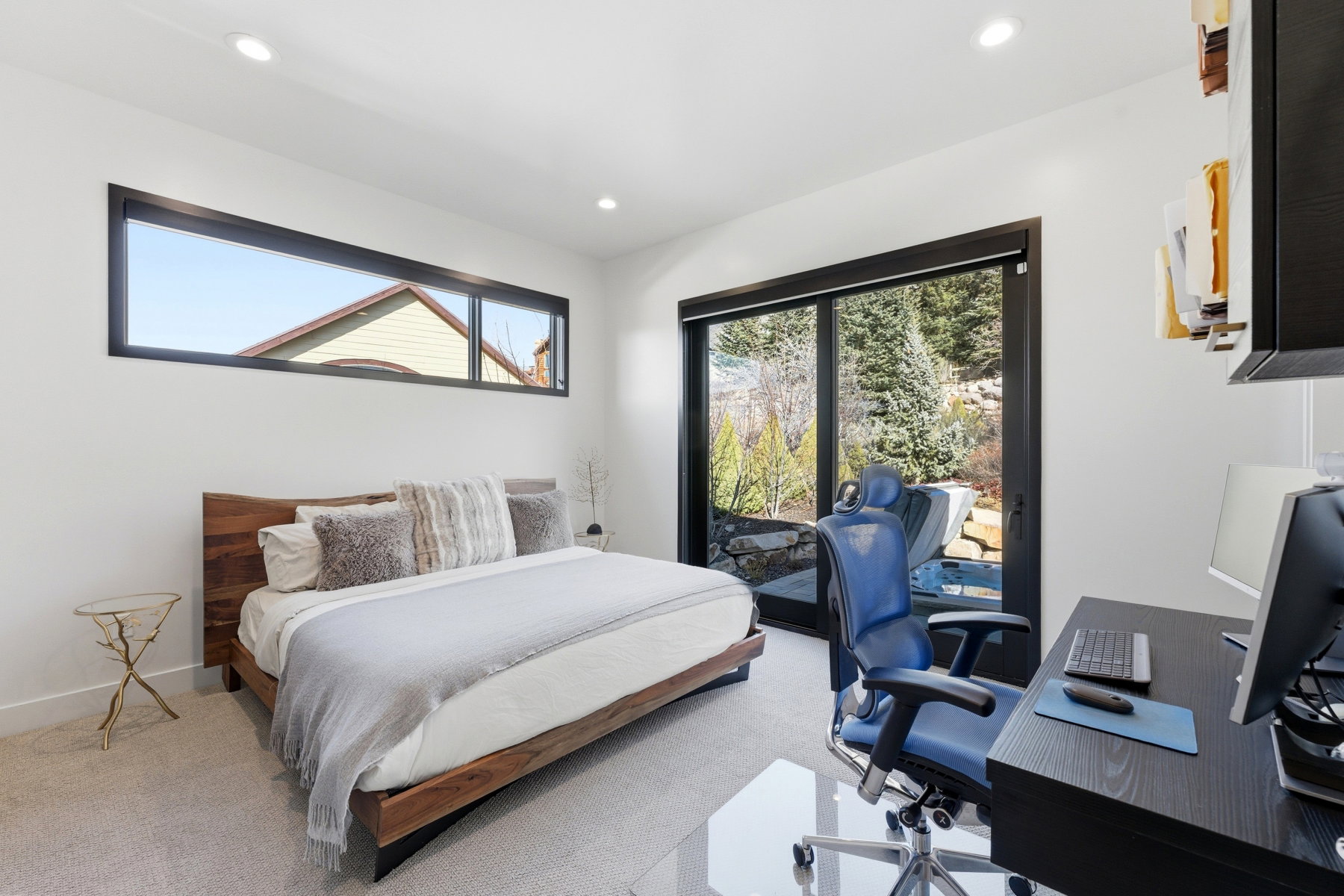 Spacious room featuring a large wood-frame bed, a wide horizontal window, and a full-height glass door