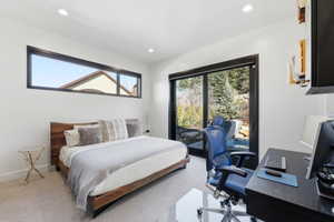 Spacious room featuring a large wood-frame bed, a wide horizontal window, and a full-height glass door