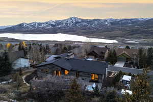 Rustic-style residence featuring a dark-toned exterior, a sloped dark roof, and a prominent stone chimney