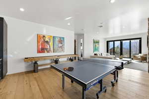 Spacious entertainment room featuring wood-finish flooring, recessed lighting, and a shuffleboard table
