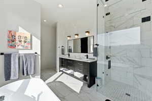 Contemporary bathroom featuring a spacious glass-enclosed shower with white subway tile, a freestanding soaking tub, a dual vanity with dark cabinetry, and white marble-look flooring
