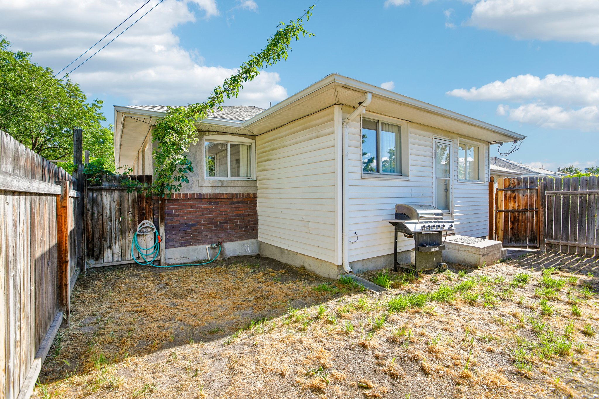 Rear exterior with white siding and a wood privacy fence