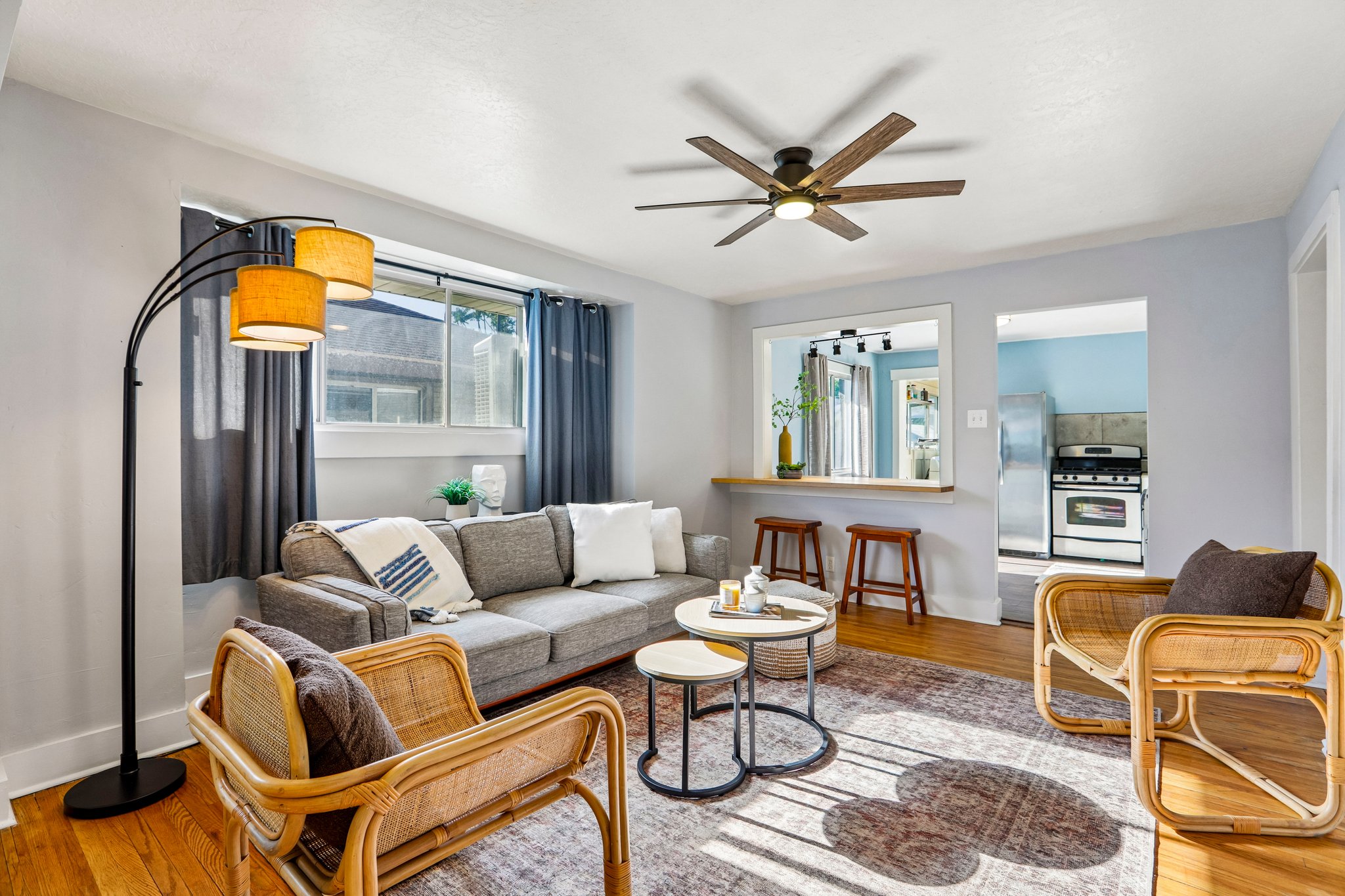 Living area featuring wood-finish flooring, a ceiling fan with integrated lighting, and a pass-through window with a built-in counter