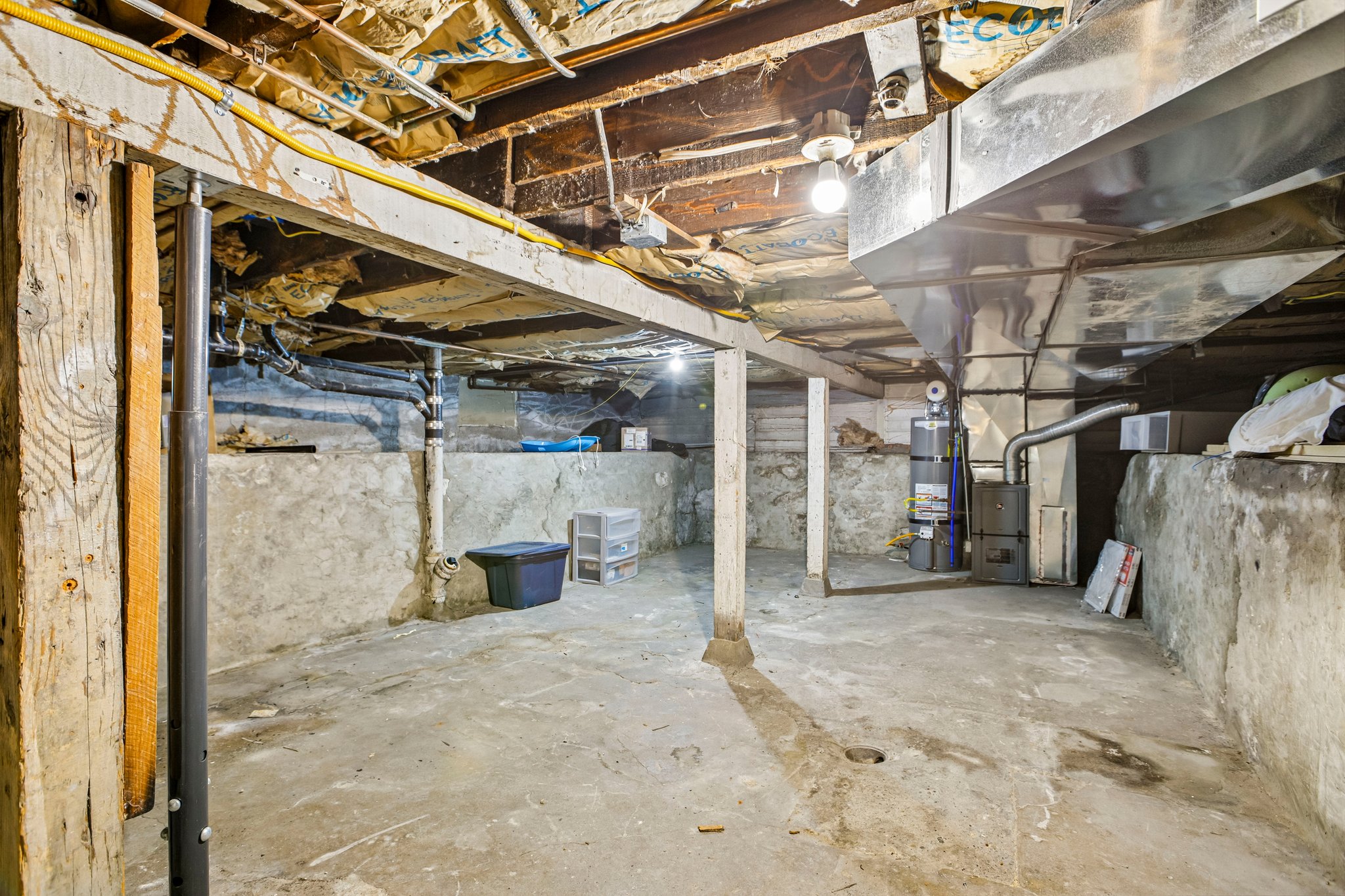 Unfinished basement featuring exposed wood joists, concrete flooring, and foundational walls