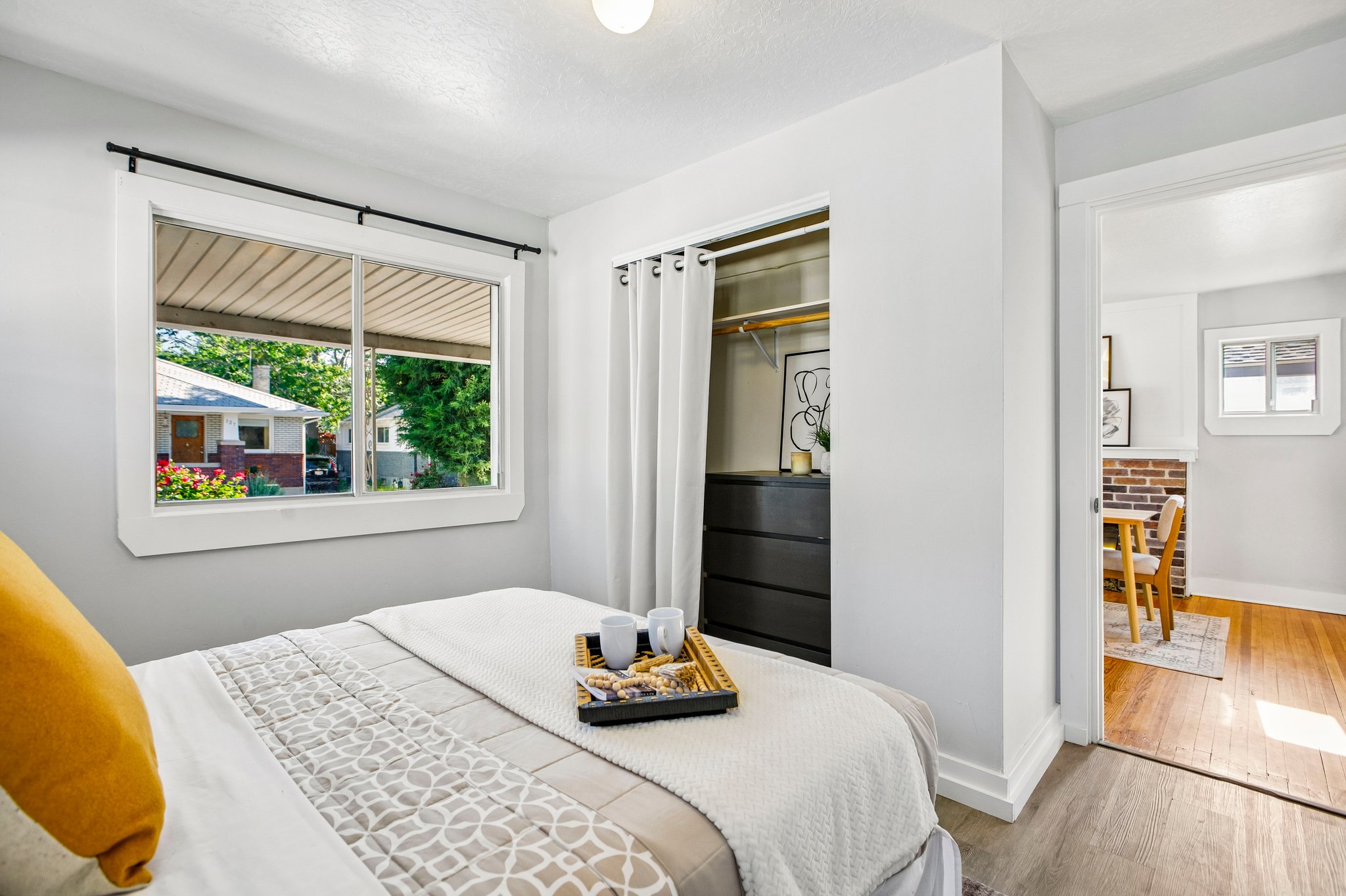 Bedroom featuring light gray walls, wood-finish flooring, a window with white trim, and a closet with a clothing rod