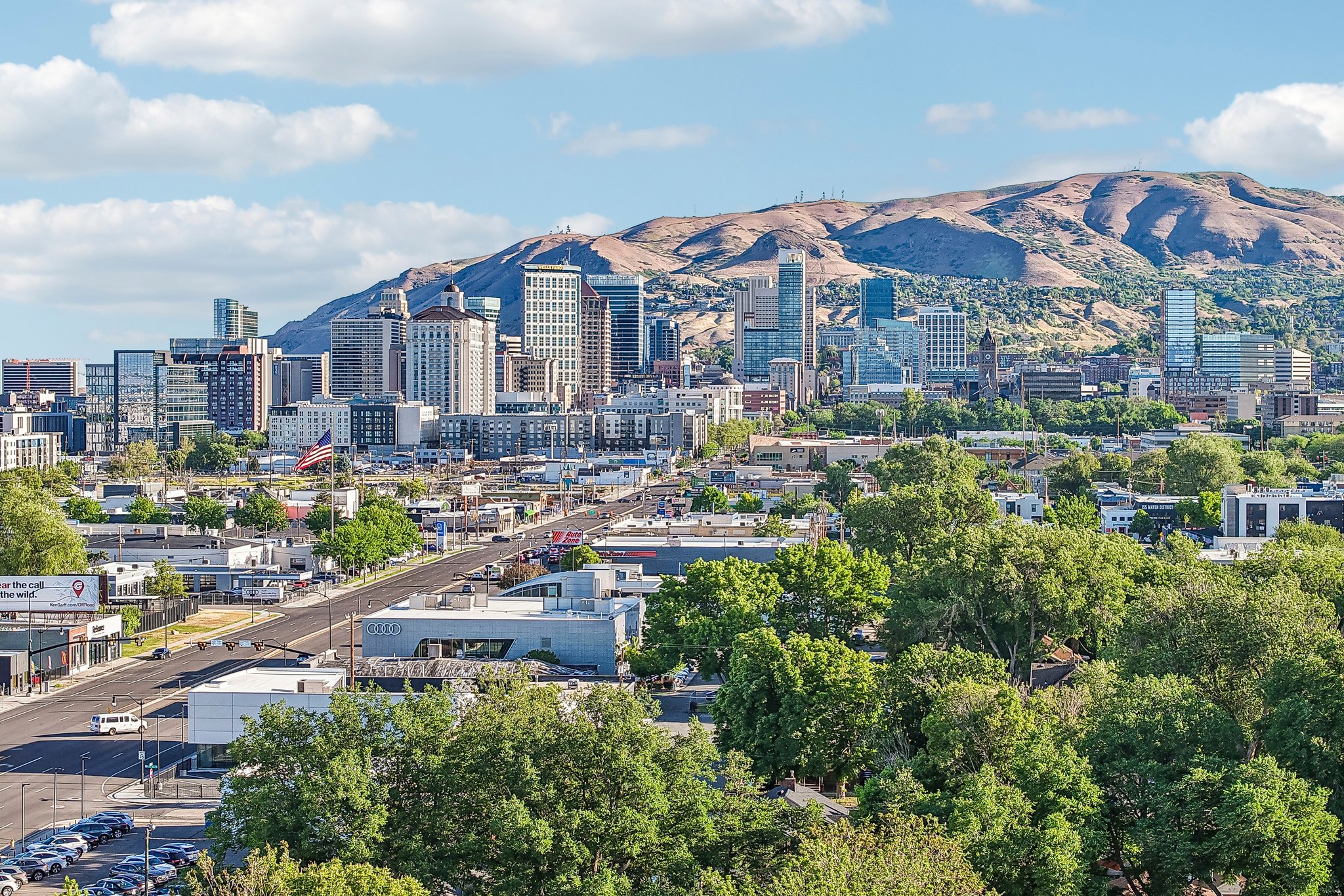 Expansive city skyline with numerous high-rise buildings set against a backdrop of rolling mountains