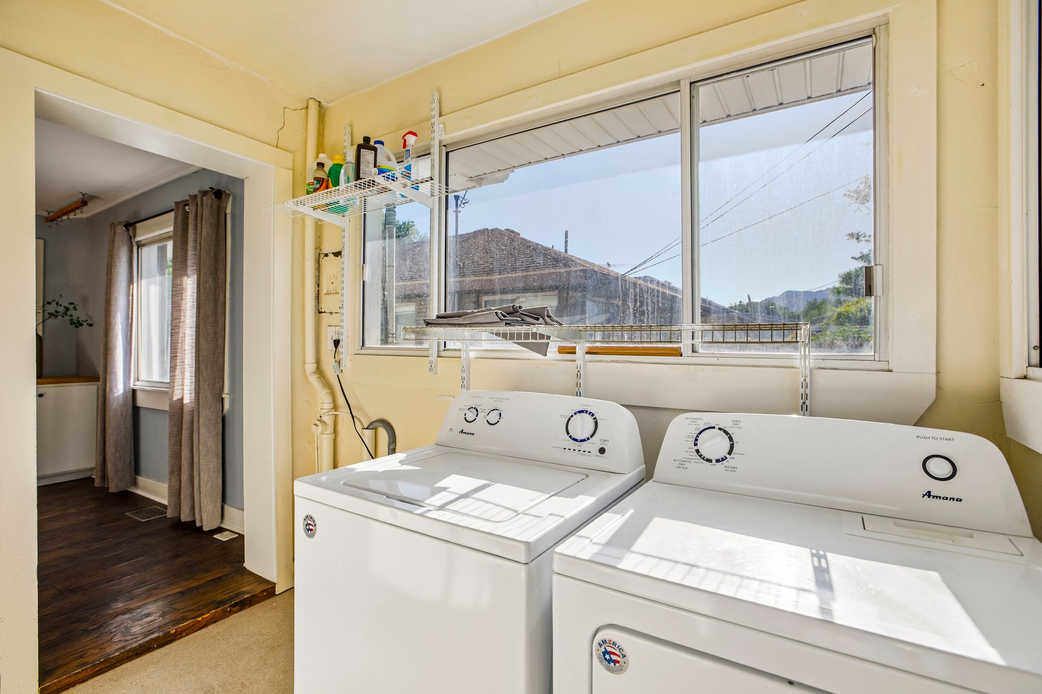 Dedicated laundry area with a large window, integrated shelving, and a hard surface flooring transition