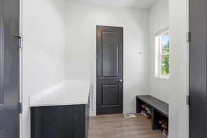 Entryway featuring wood-finish flooring, a built-in bench with shoe storage, and a white countertop with dark cabinetry