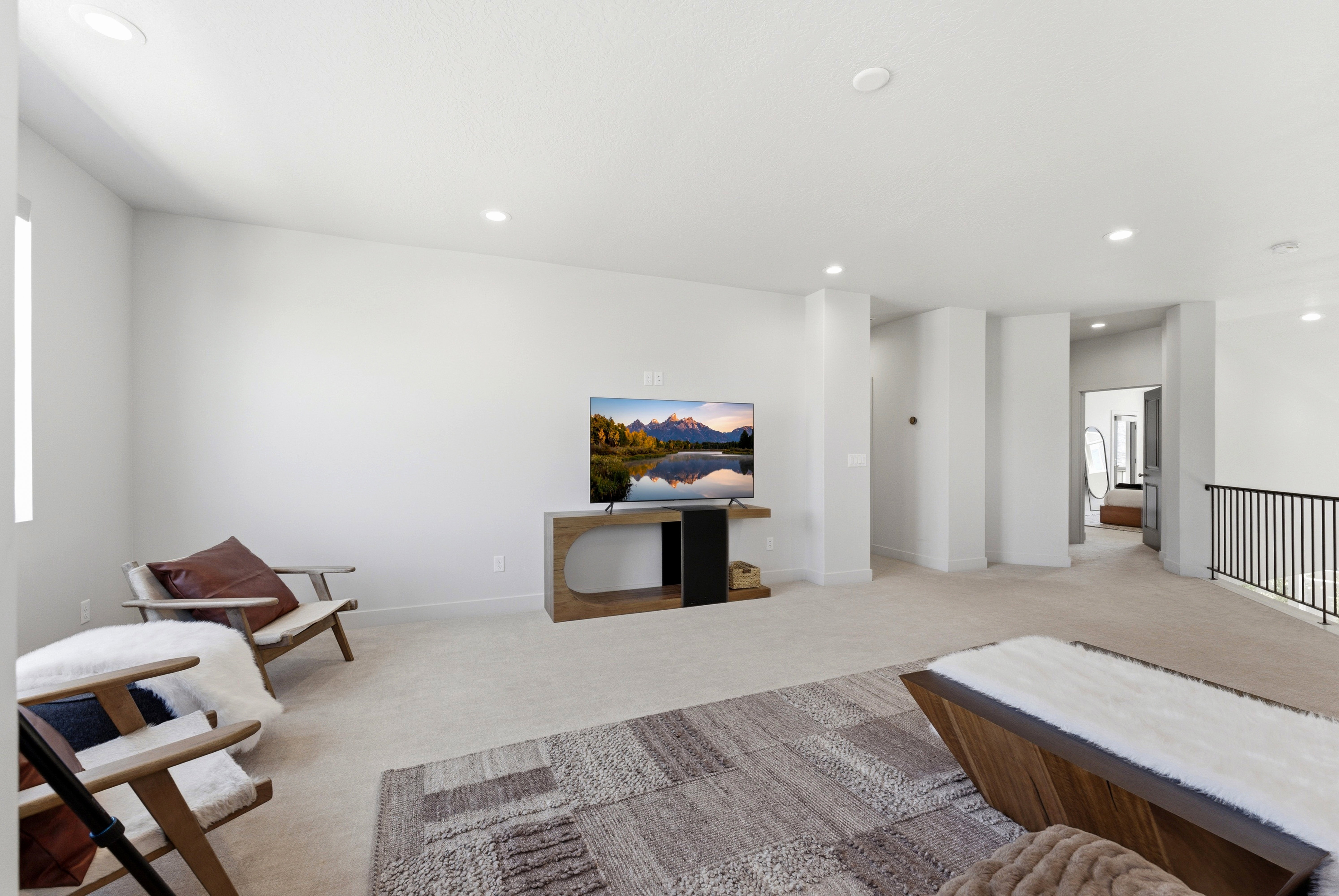 Spacious loft area featuring light-toned carpeting, recessed lighting, and a modern black metal railing