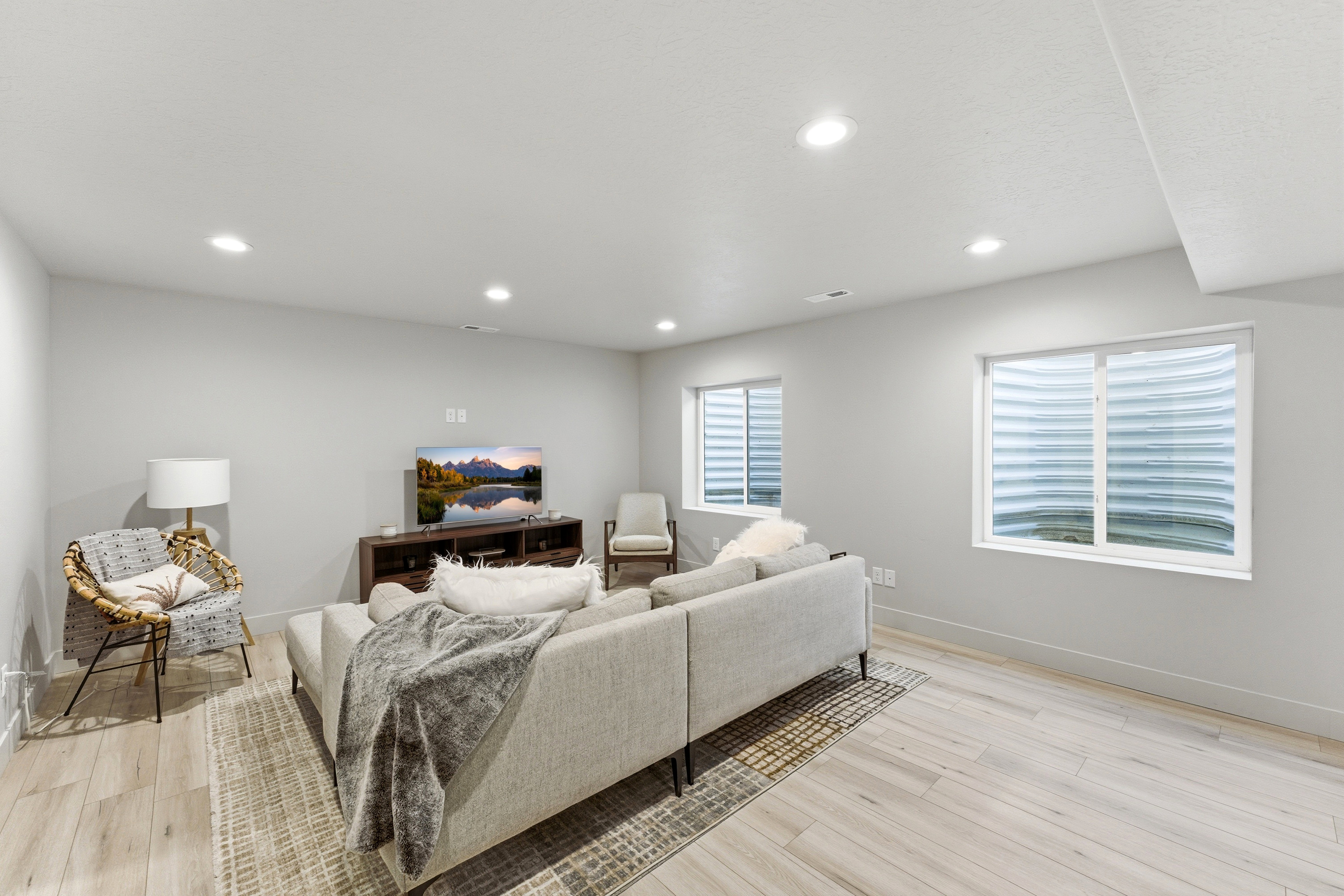Spacious living area featuring light-toned LVP-finish flooring, recessed lighting, and light gray walls