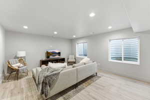 Spacious living area featuring light-toned LVP-finish flooring, recessed lighting, and light gray walls