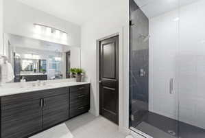 Vanity featuring a white countertop with an undermount sink, wood-finish cabinetry, and a wide mirror