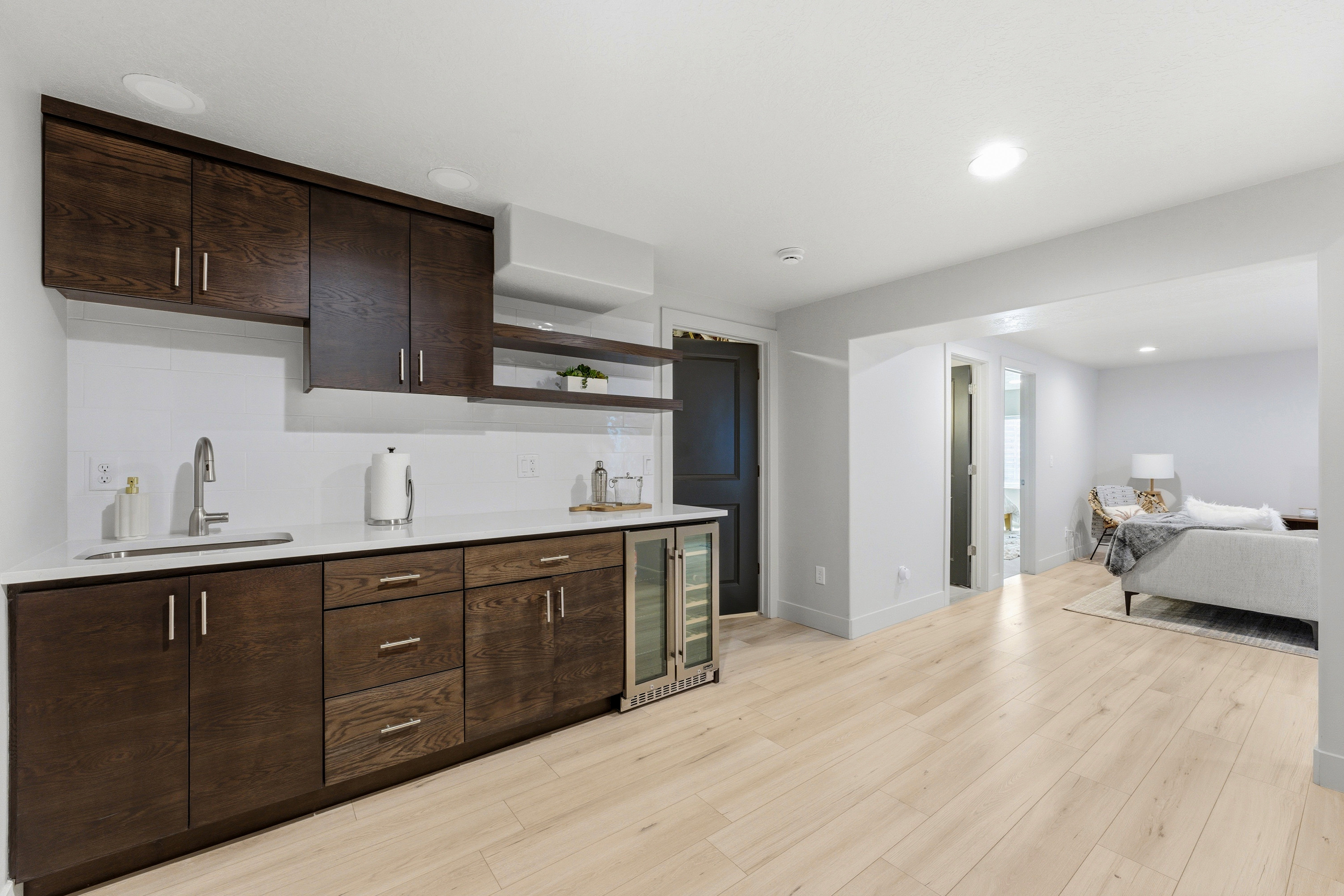 Wet bar featuring dark wood cabinetry, white countertops, stainless steel sink, and built-in beverage refrigerator