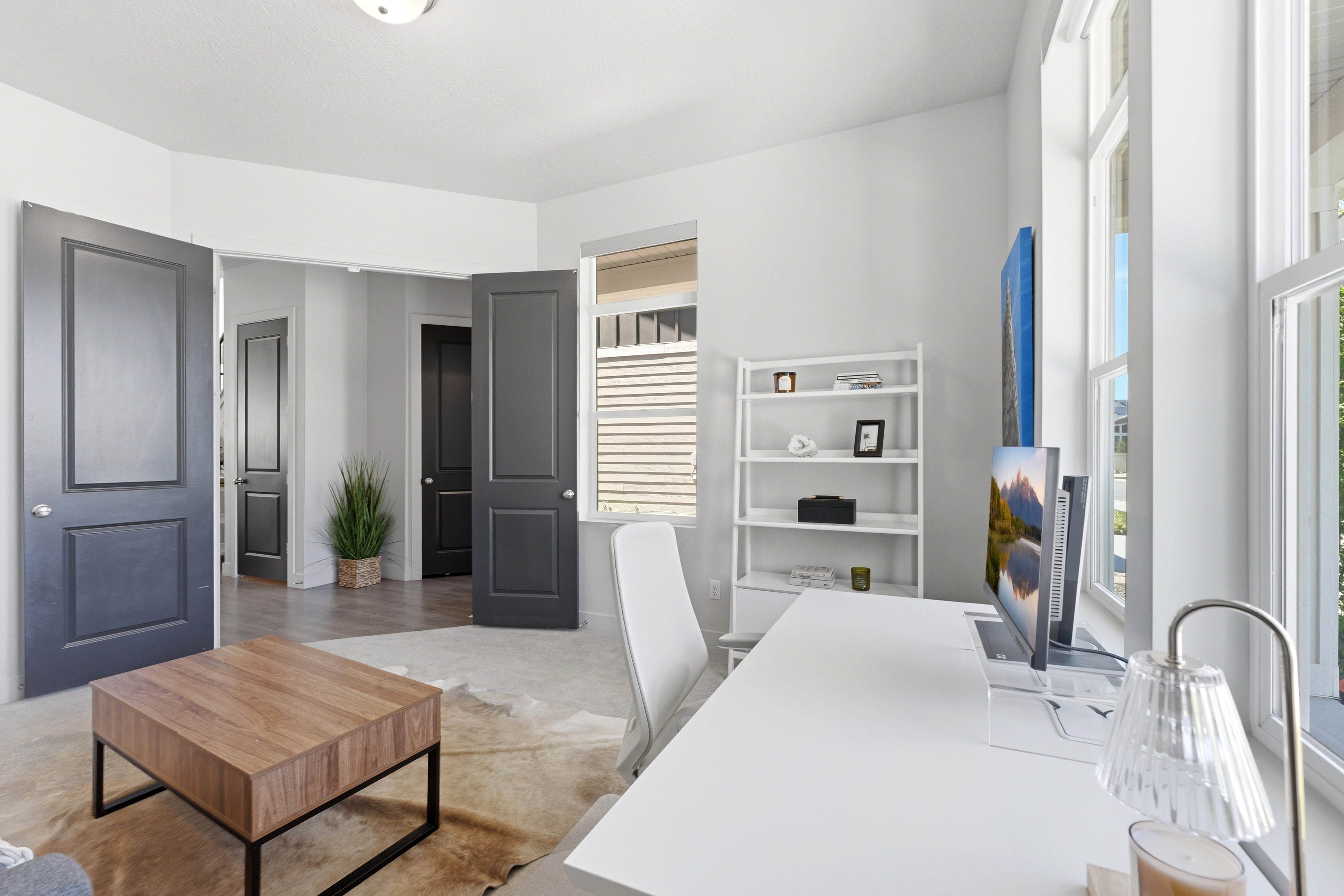 Bright room featuring large windows, white walls, and dark interior doors