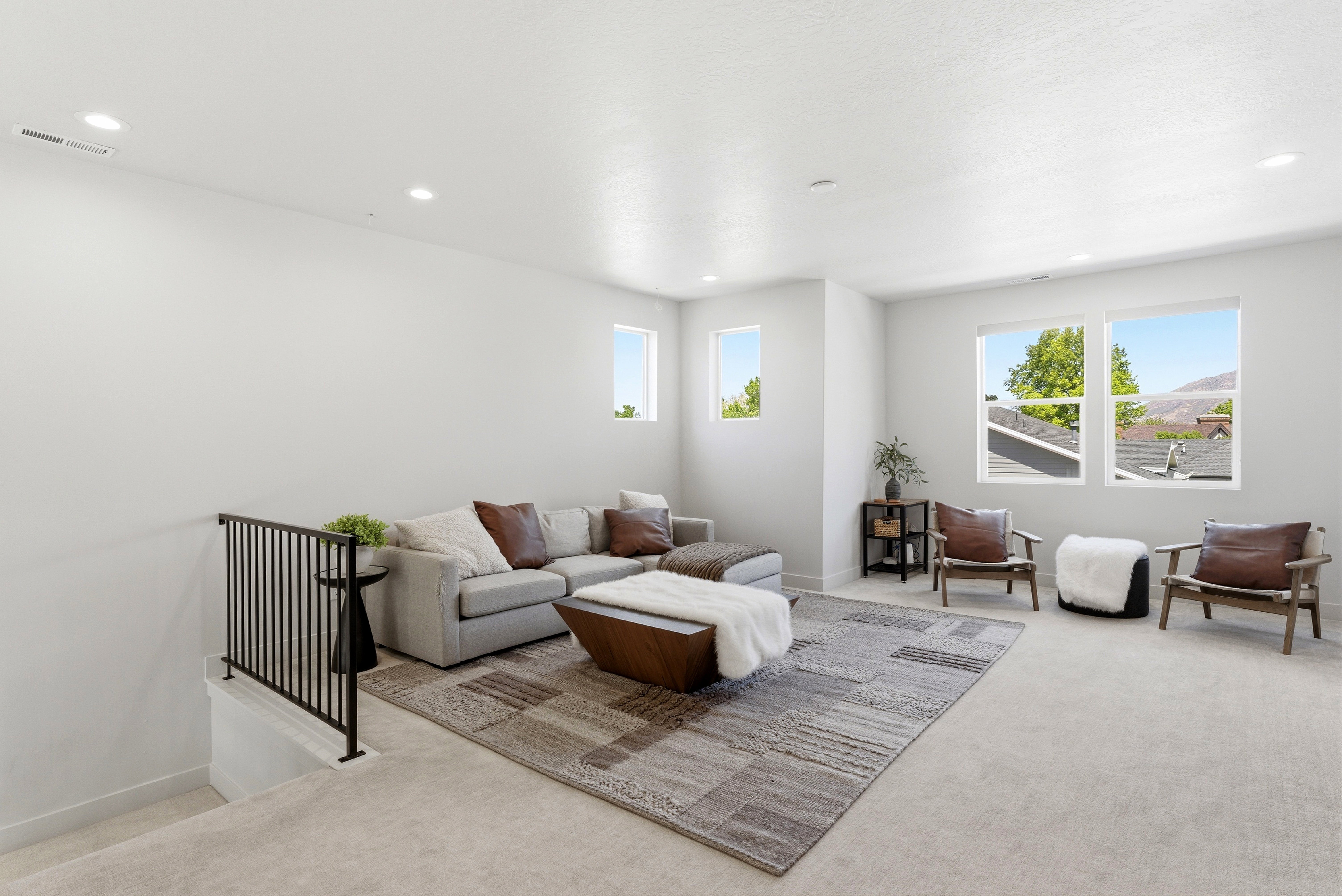 Spacious upper-level room featuring multiple windows, recessed lighting, and light-colored carpeting