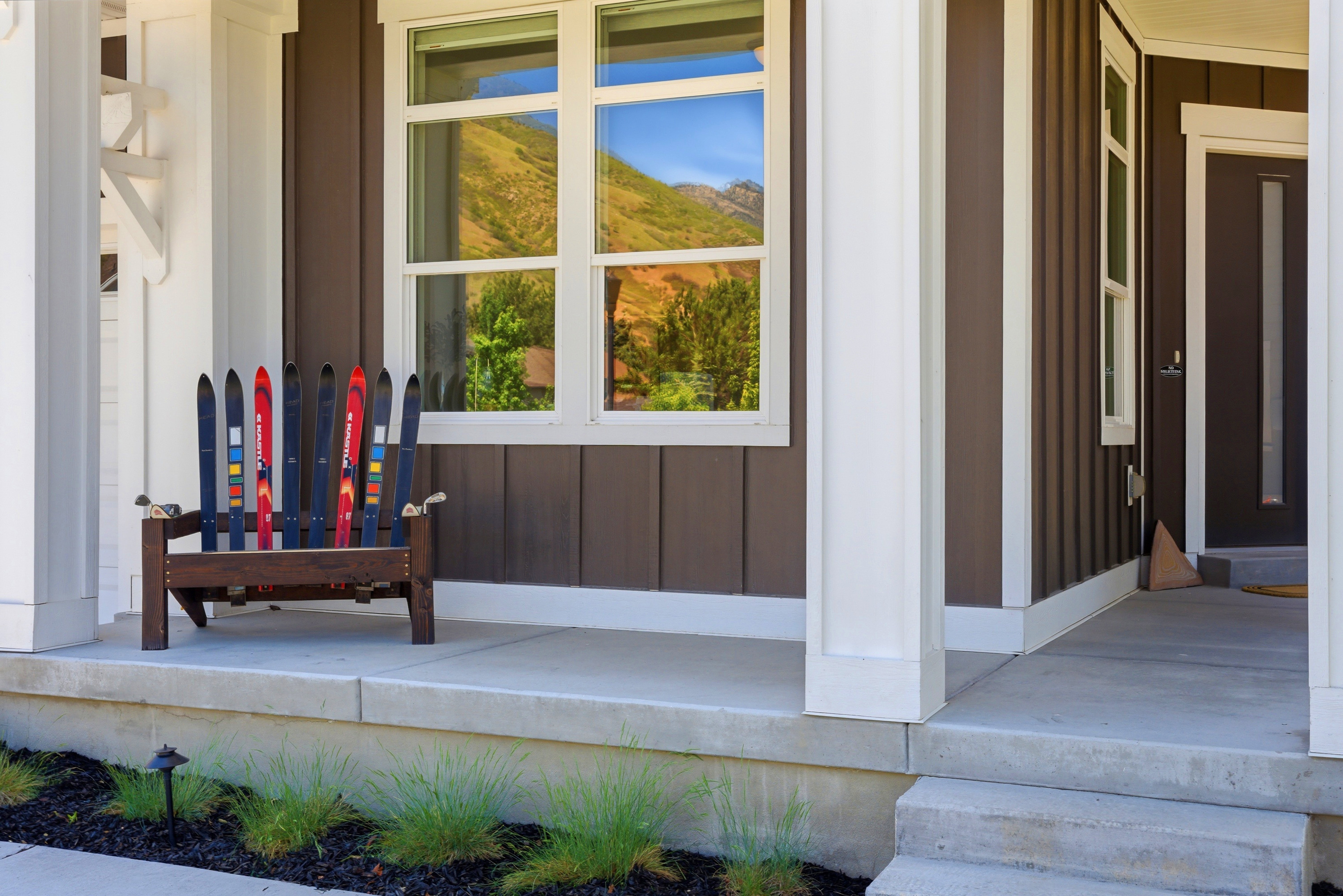 Front porch with board-and-batten siding in a deep brown hue, contrasted by bright white trim and columns