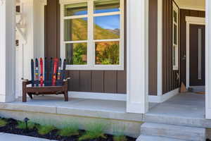 Front porch with board-and-batten siding in a deep brown hue, contrasted by bright white trim and columns