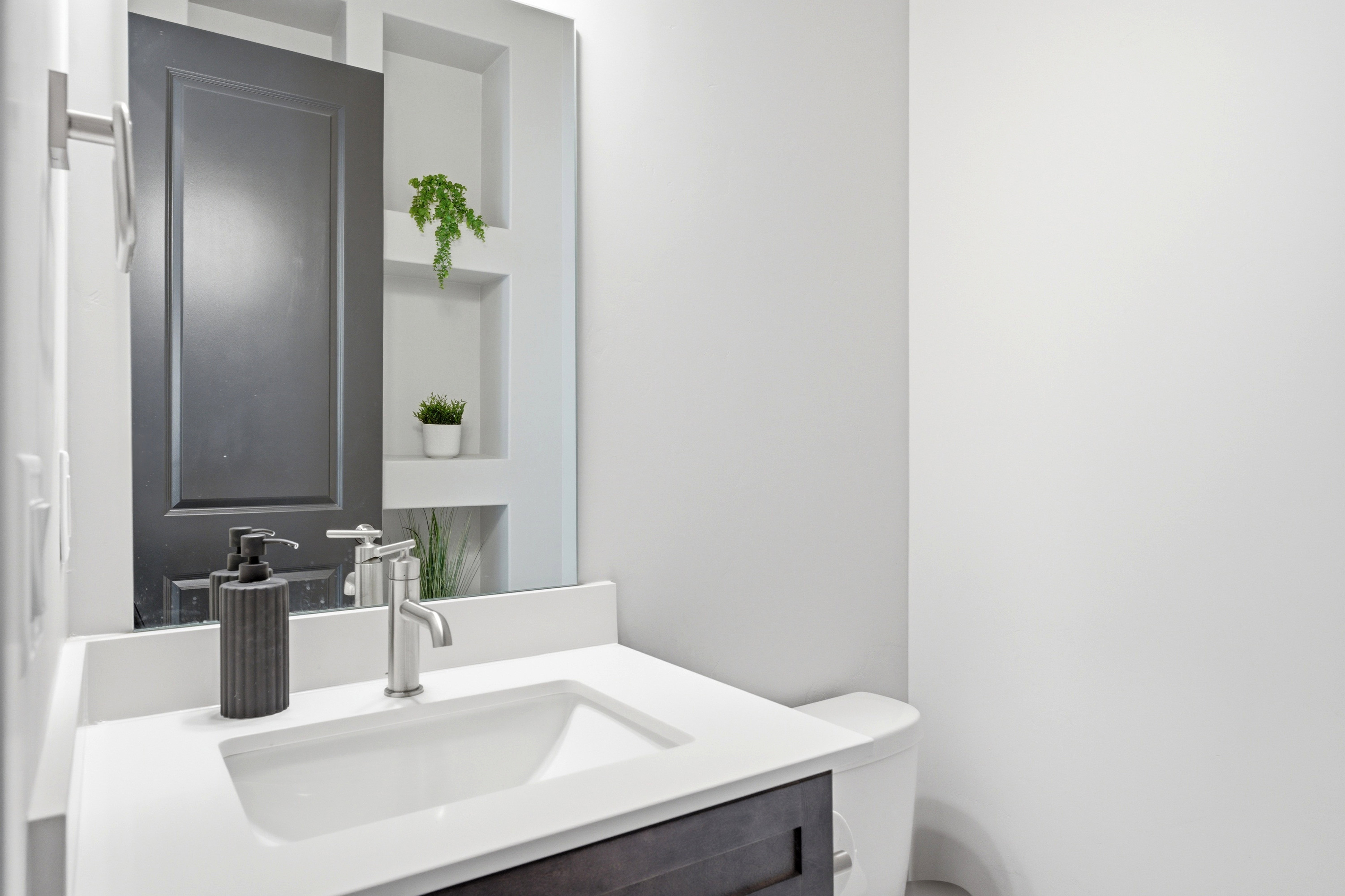 Bathroom vanity with an integrated rectangular sink, white countertop, dark wood-finish cabinetry, and a contemporary chrome faucet